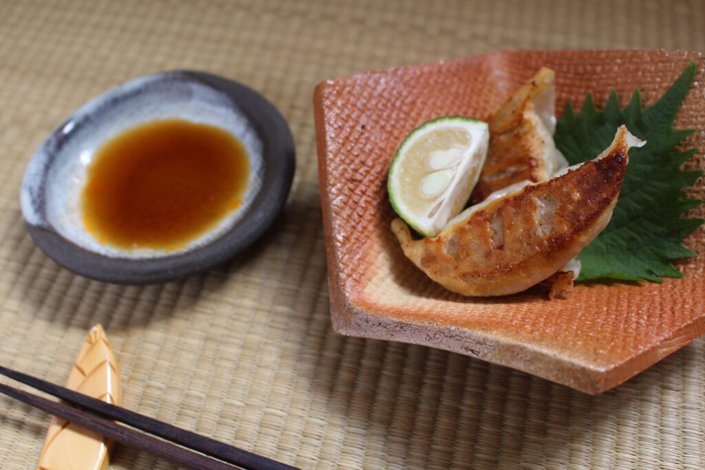 青しそとすだちを添えた焼き餃子とタレとお箸